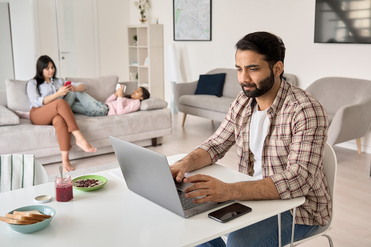 Busy parent using laptop in home office having virtual meeting
